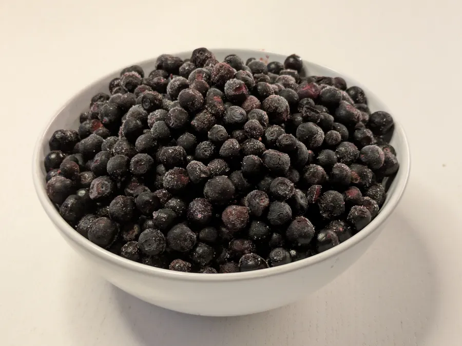 Blueberries thawing in a white bowl.