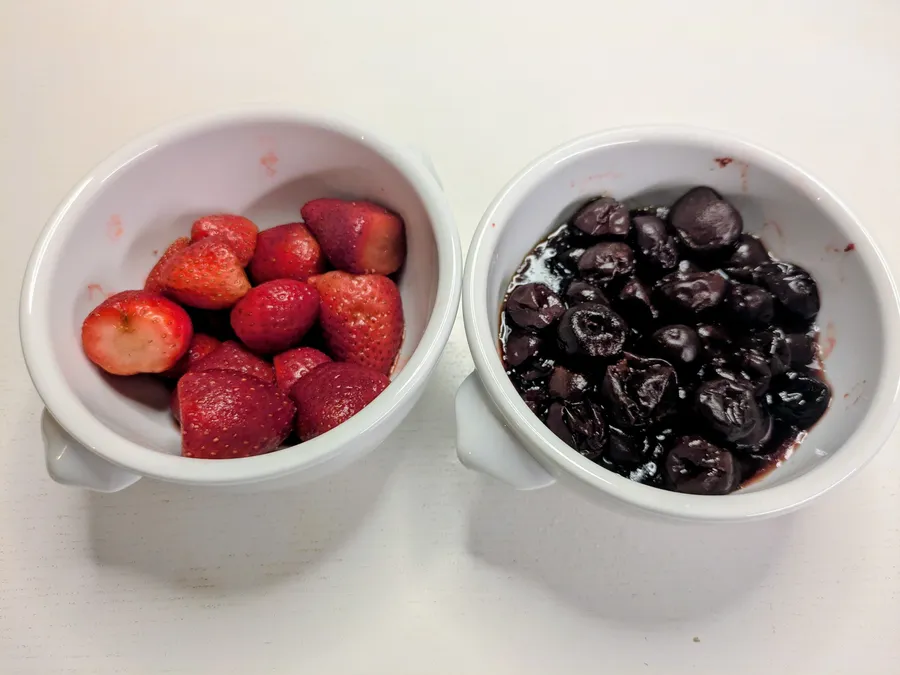 Cherries and strawberries in two bowls.
