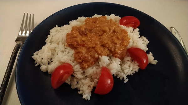 Spicy red lentil stew with rise and a tomato