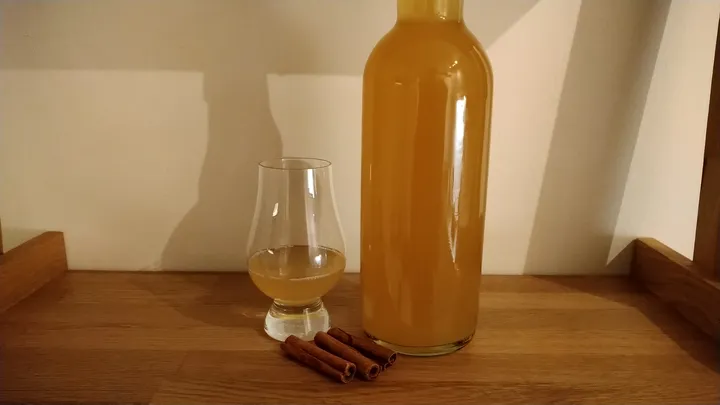 Cinnamon mead in bottle and glas and three cinnamon sticks.