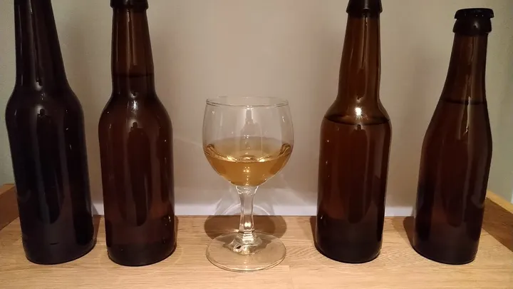 Metheglin chili mead in a glass and four dark bottles.
