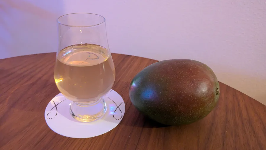 Mango mead in glencairn glas besides a mango.