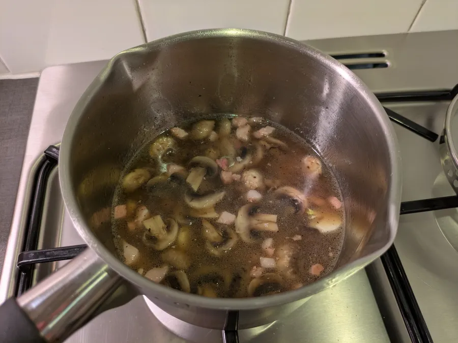 Boiling soup with bacon, mushrooms and garlic