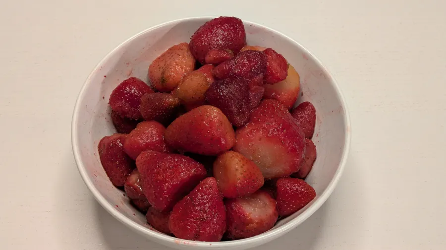 Strawberries thawing in a white bowl.