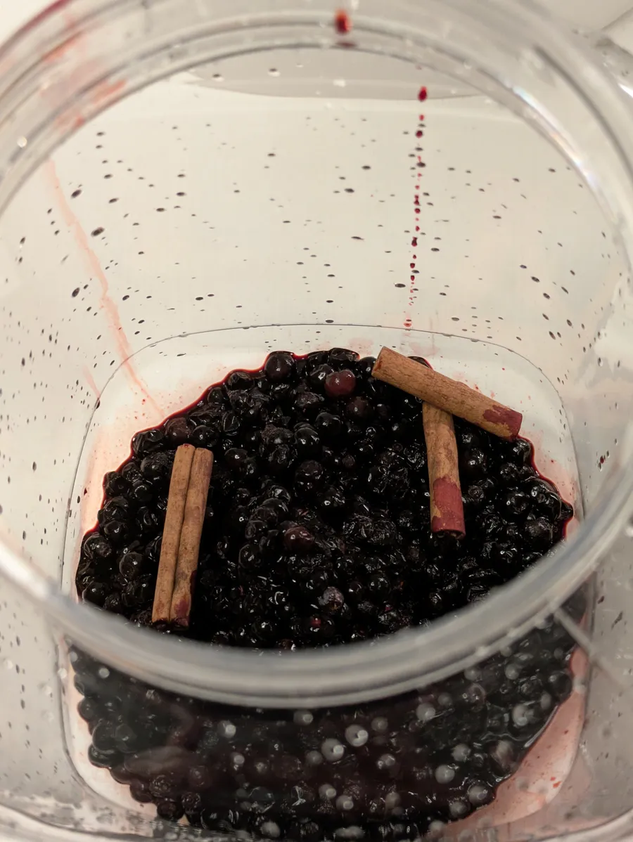 Three cinnamon sticks and blueberries in a bucket.